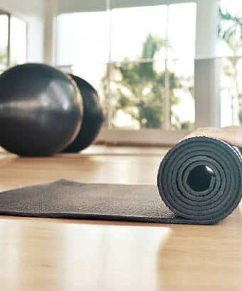 Woman rolling her mat after a yoga class on  wooden floor
